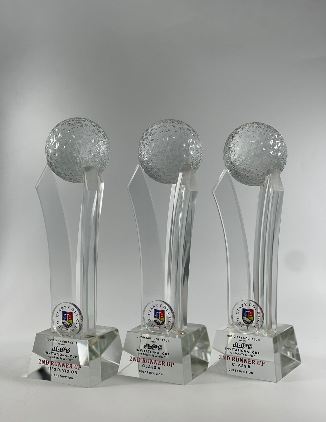 Three crystal golf ball trophies on a gray background
