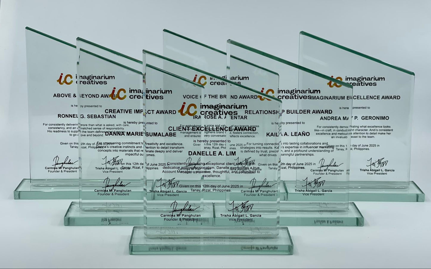 Set of glass awards with engraved text and signatures on a white background