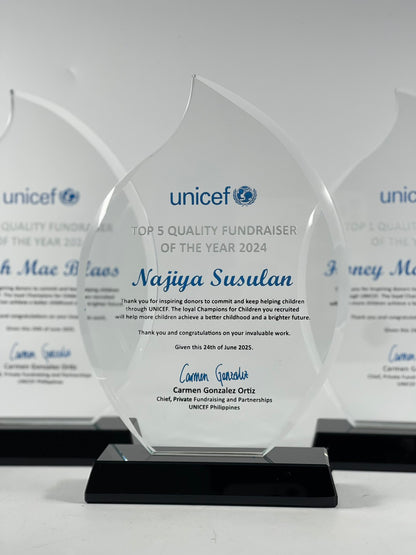 UNICEF award for Top 5 Quality Fundraiser of the Year 2024 to Najia Susulan, with a clear glass award and black base.