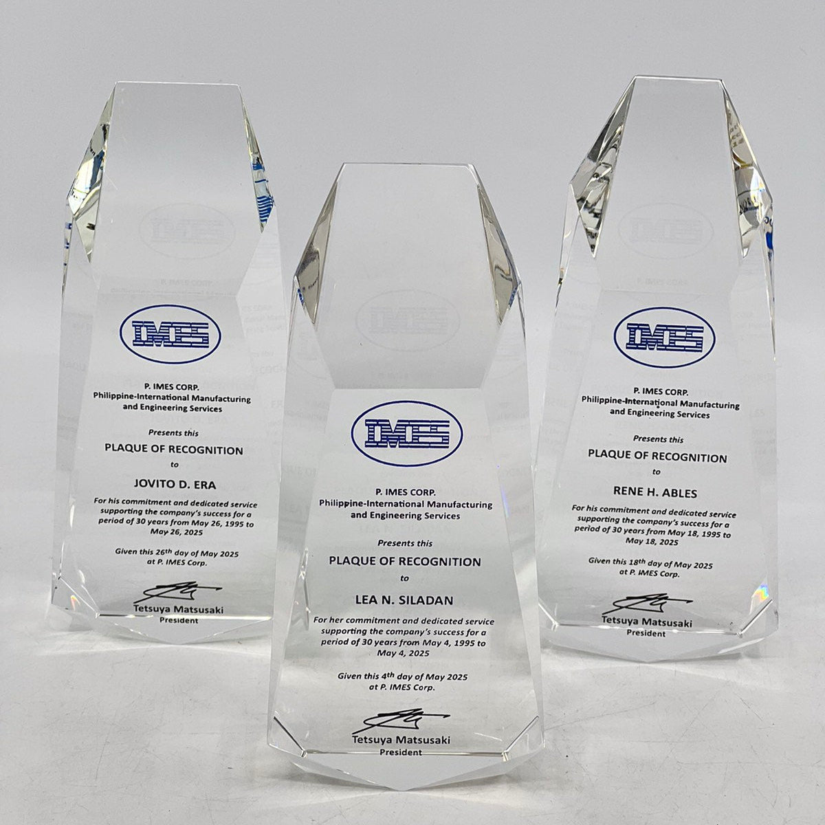 Three crystal awards with engraved text on a white background